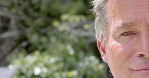 Mature Man Contemplatively Staring Outdoors Amidst Lush Greenery