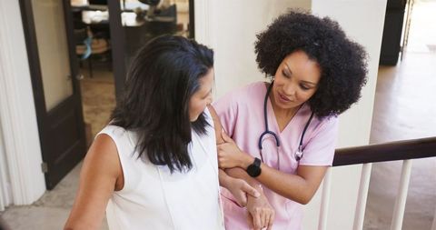 Nurse assisting woman down stairs in healthcare facility
