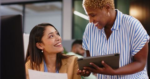 Two women collaborating in office on project using tablet