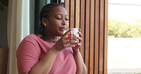 African american woman sipping tea at doorway enjoying quiet morning ritual and calm