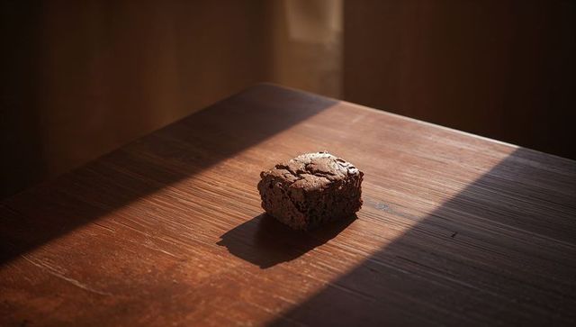 Single Rustic Chocolate Brownie Bathed in Warm Sunbeam on Textured Wooden Table