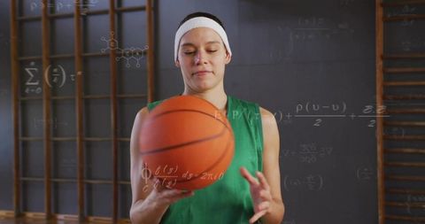 Female athlete holding basketball in gym with mathematical formula chalkboard overlay