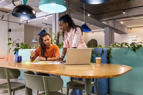 Diverse coworkers collaborating and brainstorming at modern coworking table