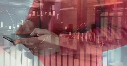 Man holding smartphone scrolling candlestick stock charts overlay in contemporary office
