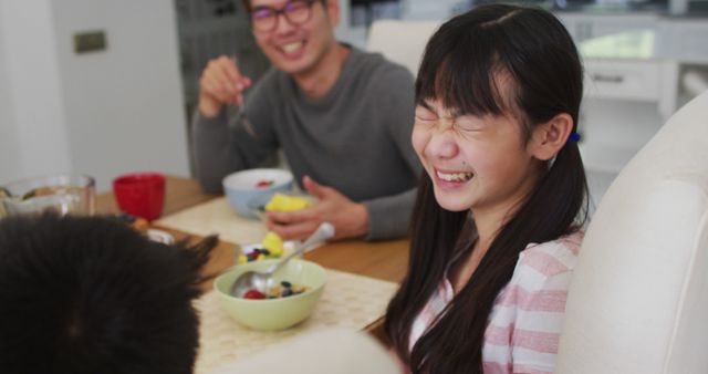Happy asian father in kitchen eating breakfast with laughing son and daughter. happy family, at home in isolation during quarantine lockdown.