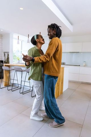 African American couple dancing and holding hands in modern minimalist kitchen