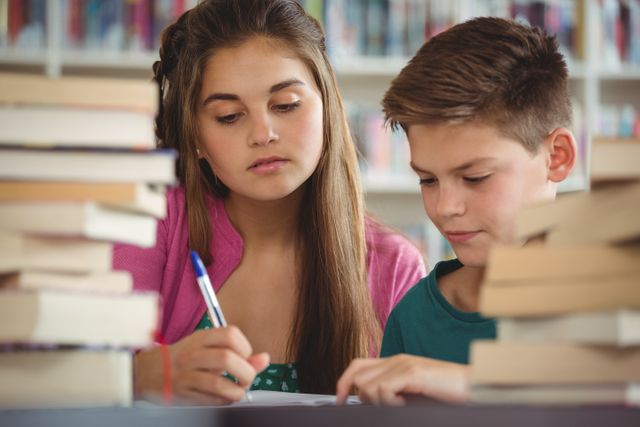 Two students are diligently working on their homework in a library, surrounded by stacks of books. This image can be used for educational content, school promotions, library programs, or articles about student life and academic success.