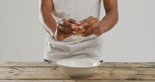 Person Cracking Egg into Bowl on Wooden Table - Download Free Stock Images Pikwizard.com