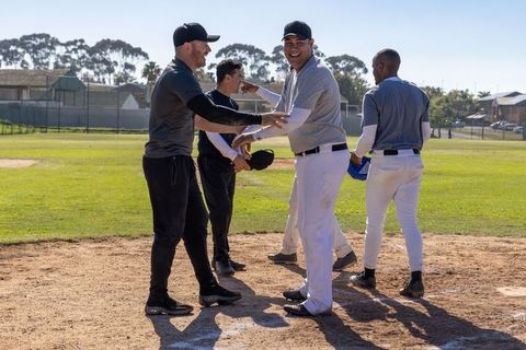 Baseball teammates celebrating after game handshakes on sunny community ballfield
