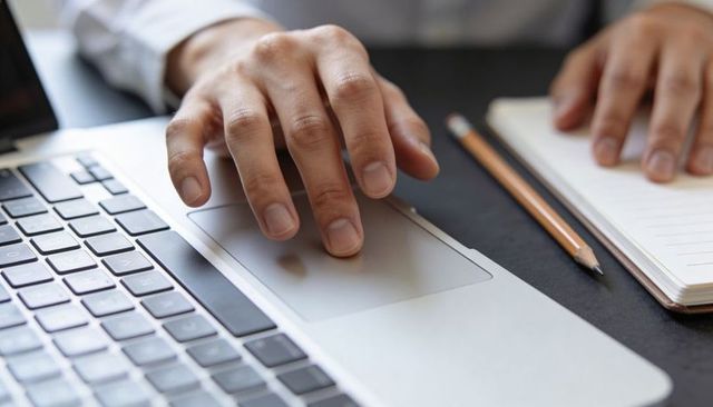 Right Hand Navigating Laptop Trackpad with Notebook and Pencil for Office Productivity