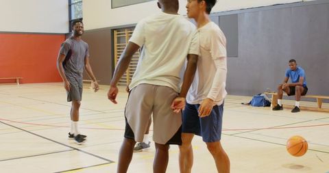 Young men playing pickup basketball on indoor gym court showing teamwork and motion