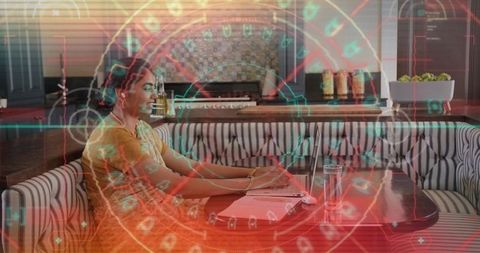 Woman in yellow kurta typing on laptop at cafe booth with augmented reality hud overlay