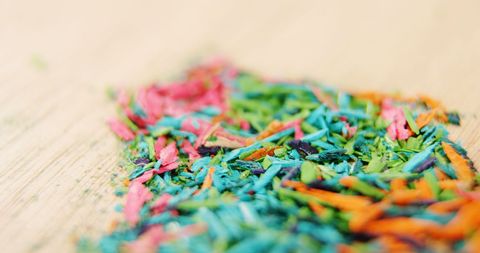 Colorful pencil shavings on wooden surface close-up