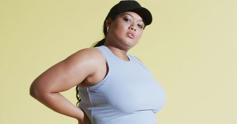Confident Woman in Athletic Wear Against Yellow Background