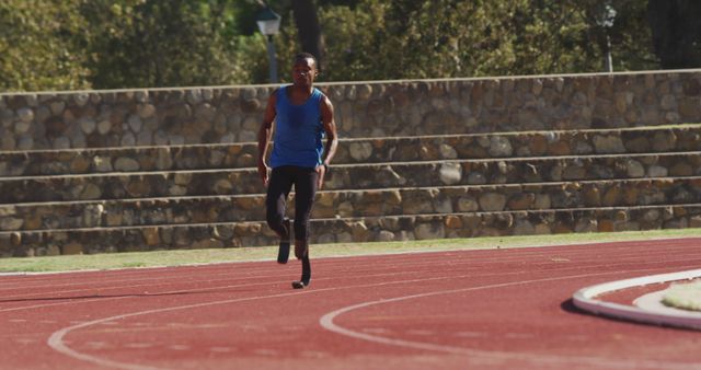 African american male athlete with prosthetic legs training at empty stadium. Sport, disability, atletics and fitness, unaltered.