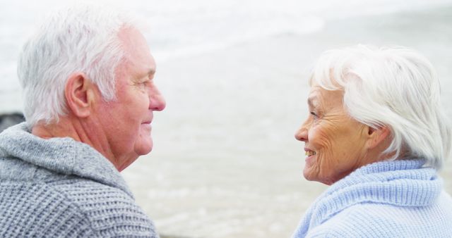 Elderly couple stands close by the beach, smiling and enjoying their time together. This can be used for themes related to retirement, love, bonding, healthy lifestyle, and happiness in later life. Suitable for marketing materials, retirement living brochures, or health and wellness magazines.