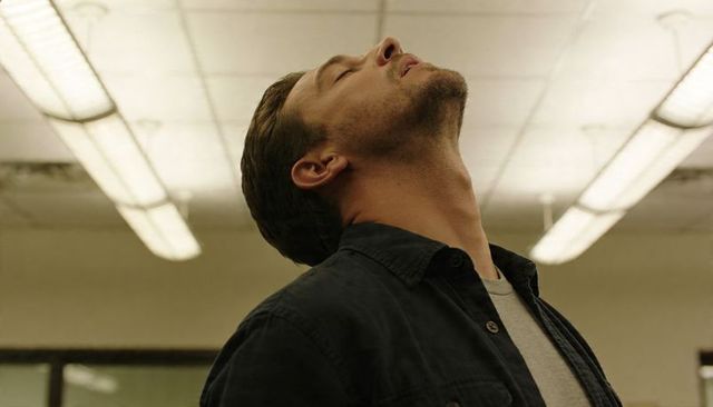 Man leaning head back under fluorescent ceiling lights conveying fatigue and contemplation