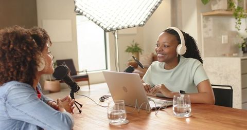 Women recording podcast in home studio with microphones, laptop, softbox lighting