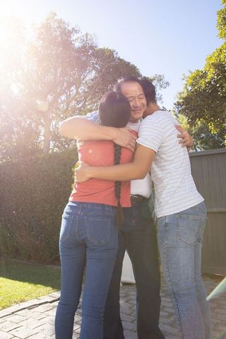 Asian Family Embracing in Garden with Bright Sunlight Harmony