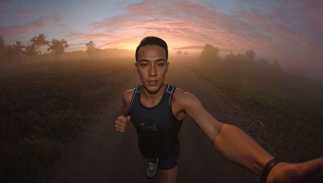 Sunrise running selfie by asian male on misty rural road for morning fitness motivation