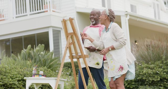 Happy senior african american couple painting picture in garden and talking. Retirement, togetherness, creativity, hobbies and senior lifestyle, unaltered.