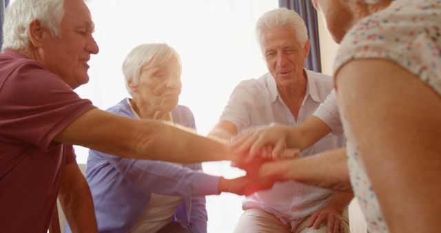 Senior friends joyfully engaging in group handshake, showcasing unity and togetherness. Perfect for use in marketing materials related to senior living, community engagement, elderly activities, and social connections among retirees.