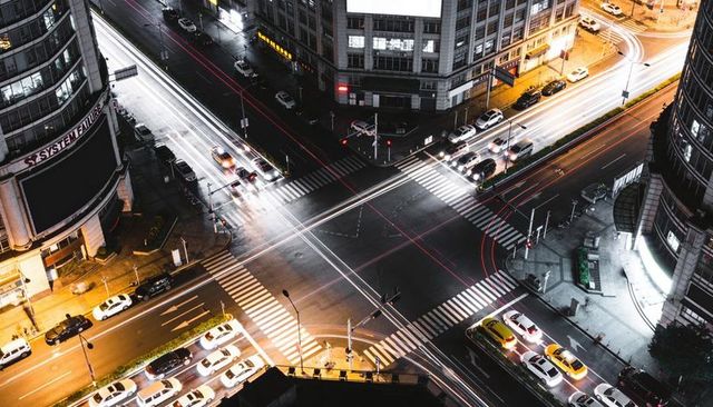 Nighttime city intersection with diagonal crosswalks and streaking car light trails