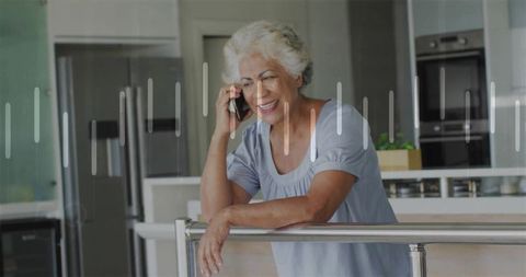 Smiling senior woman using smartphone in bright modern kitchen