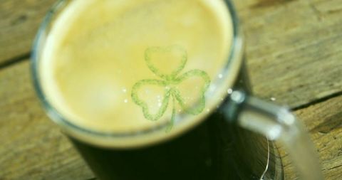 Green mug resting on wooden table with shamrock latte art for st patrick's day