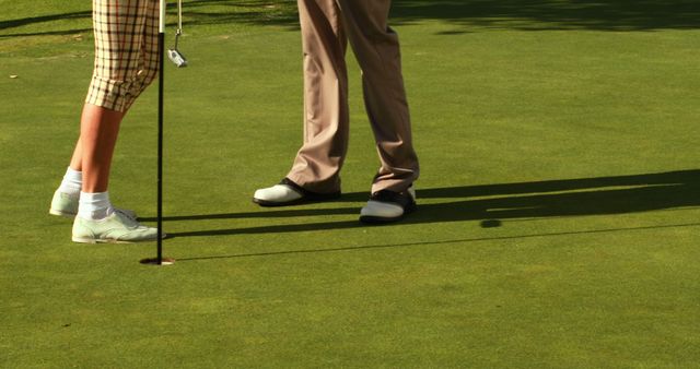 Golfers on Green Near Hole with Shadows on Grass - Download Free Stock Images Pikwizard.com