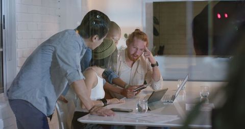 Diverse Team Collaborating in Office Meeting with Laptops and Documents