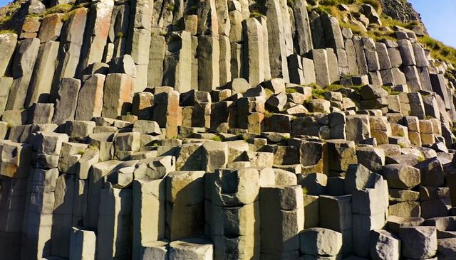Hexagonal basalt columns forming stepped terraces on coastal cliff for design and education