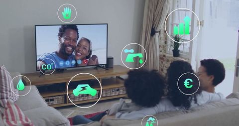 Family watching tv on sofa with smart home sustainability and energy icons overlay