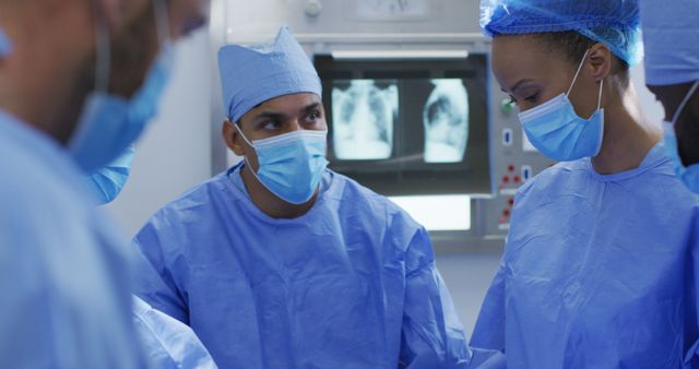 Doctors and healthcare professionals in blue surgical gowns and face masks are working together in an operating room, performing a medical procedure. This image may be suitable for use in medical blogs, healthcare articles, hospital websites, or promotional materials for medical services. The teamwork of the doctors highlights the professional dedication and collaboration in a clinical setting.