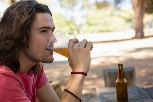 Man drinking beer from disposable glass in the park