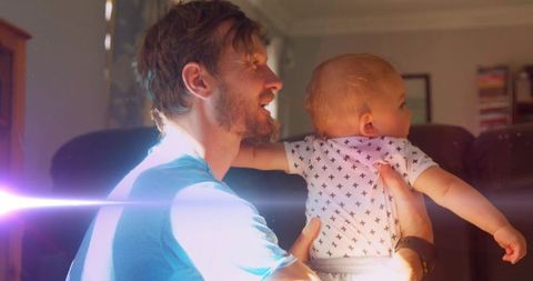 Warm Family Moment: Father Holding Baby with Lens Flare Effect