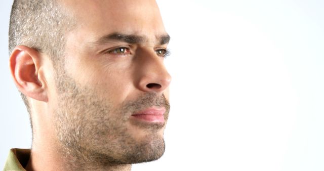 This image shows a close-up of a pensive man looking into the distance. His expression is serious and contemplative, suggesting deep thought or reflection. The clear background highlights the details of his face. This image can be useful for illustrating concepts related to introspection, decision-making, thinking, and personal reflection. Suitable for articles, blog posts, advertisements, or any other creative projects focusing on mental or emotional subjects.