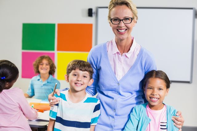 Portrait of smiling teacher and kids standing together with arm around in classroom