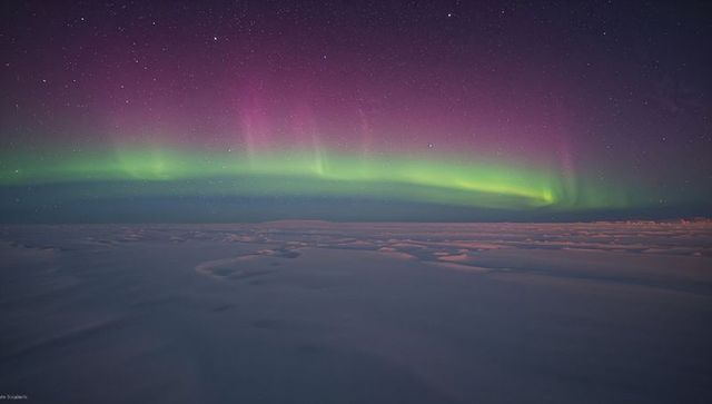 Dancing Aurora Borealis Arching Over Snowy Arctic Plain Under Starry Purple-Green Sky