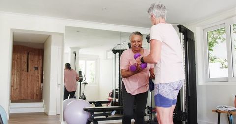 Senior Couple Exercising Together with Dumbbells at Home Gym