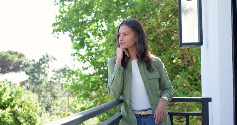 African american woman leaning on balcony railing, contemplating future in casual denim
