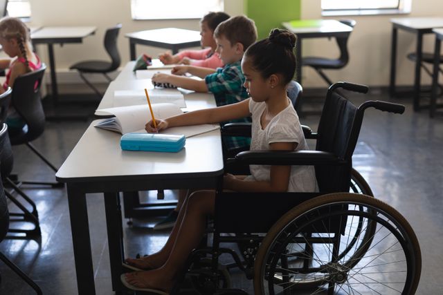This image shows a young disabled schoolgirl in a wheelchair studying alongside her classmates in an elementary school classroom. The children are focused on their work, highlighting themes of inclusion, diversity, and education. This image can be used for educational materials, articles on inclusive education, school brochures, or campaigns promoting diversity and equal opportunities in education.