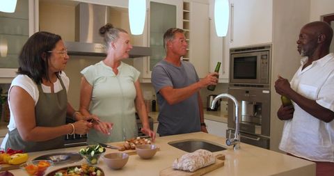 Diverse group socializing and preparing food in modern kitchen