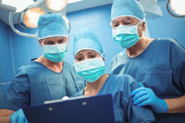 Team of surgeons discussing over clipboard in operation theater at hospital