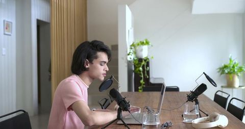 African american woman recording podcast at home with laptop and modern studio microphones