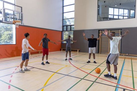 Basketball teammates practicing defensive drill on indoor court during team warmup session