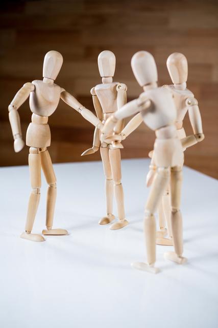Wooden mannequins stacking hands in a gesture of teamwork and unity. This image can be used to represent concepts of collaboration, partnership, and group support in business presentations, team-building workshops, and educational materials.