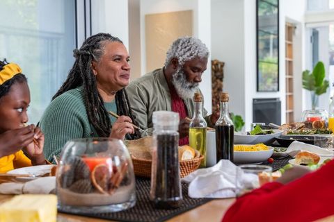 Multigenerational family sharing cozy home dinner around table with corn and olive oil
