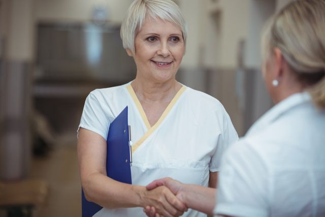 Two nurse shaking hands in corridor at hospital
