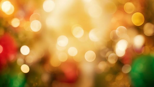 Glowing golden bokeh holiday lights creating warm festive background with red ornaments